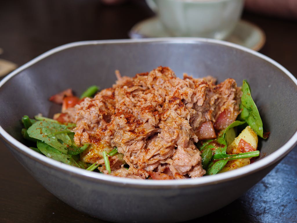 Close-up of a fresh tuna salad featuring spinach and paprika, showcasing a healthy meal option.
