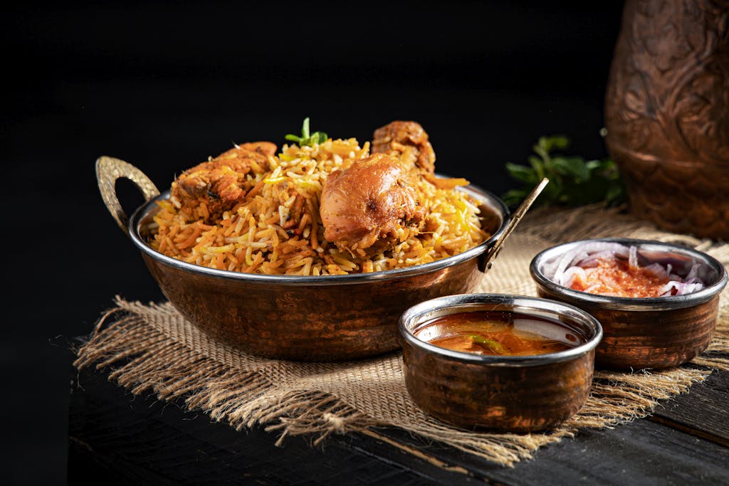 From above of delicious pilaf with rice and meat in iron pan served on table near traditional oriental soups in bowl